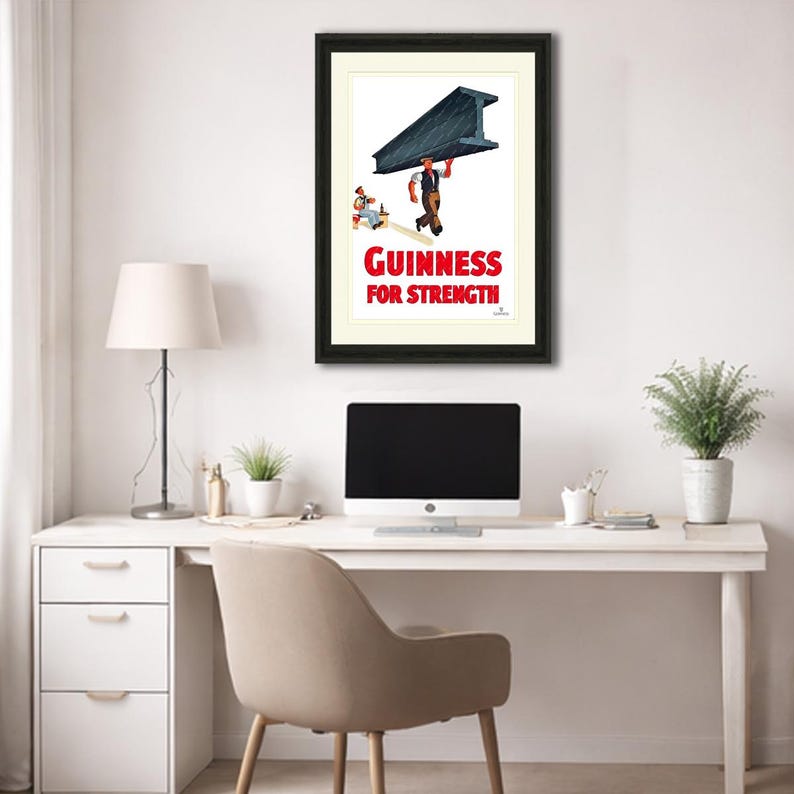 May include: Framed vintage Guinness advertisement. The print features a worker carrying a large steel beam, with the text "Guinness For Strength" in red. The artwork is set against a white background, framed in black.