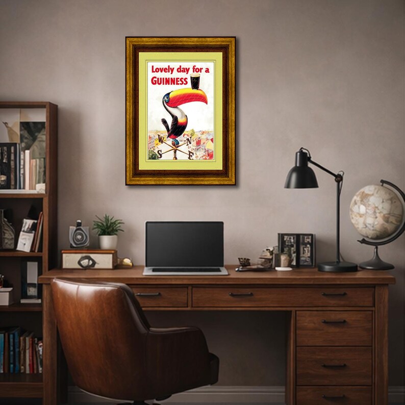 Puede incluir: Anuncio vintage enmarcado de Guinness con un tuc&aacute;n con un pico grande y colorido, sosteniendo una pinta de Guinness. El texto dice "Lovely day for a Guinness". La obra de arte est&aacute; en un marco dorado.