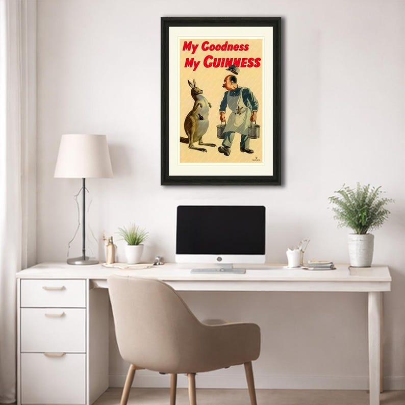 K&ouml;nnte beinhalten: Gerahmte Vintage-Guinness-Werbung mit einem K&auml;nguru und einem Mann in einer Arbeitssch&uuml;rze. Der Text "My Goodness My Guinness" ist rot. Das Kunstwerk ist vor einem cremefarbenen Hintergrund, schwarz gerahmt und an einer wei&szlig;en Wand ausgestellt.