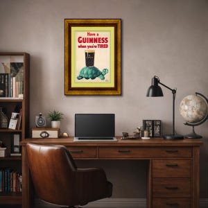 K&ouml;nnte beinhalten: Gerahmte Vintage-Guinness-Werbung. Das Kunstwerk zeigt ein Pint Guinness auf einer t&uuml;rkisfarbenen Schildkr&ouml;te mit dem Text "Have a Guinness when you're TIRED" in Rot und Wei&szlig;. Der Rahmen ist goldfarben.