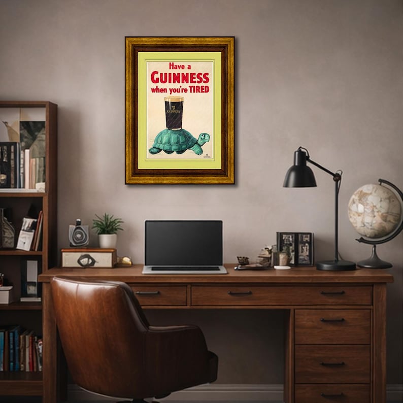 K&ouml;nnte beinhalten: Gerahmte Vintage-Guinness-Werbung. Das Kunstwerk zeigt ein Pint Guinness auf einer t&uuml;rkisfarbenen Schildkr&ouml;te mit dem Text "Have a Guinness when you're TIRED" in Rot und Wei&szlig;. Der Rahmen ist goldfarben.
