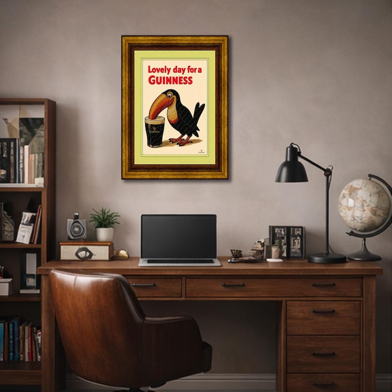 May include: Framed vintage Guinness advertisement featuring a toucan drinking a pint of Guinness. The text reads "Lovely day for a Guinness" in red letters. The artwork is in a gold-colored frame.