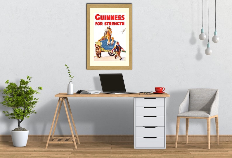 K&ouml;nnte beinhalten: Gerahmte Vintage-Guinness-Werbung. Der Druck zeigt einen Pferdewagen mit einem Mann und dem Text "Guinness for Strength" in Rot und Wei&szlig;. Der Rahmen hat eine hellbraune Farbe.