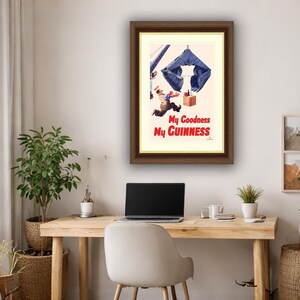 Pode incluir: An&uacute;ncio vintage emoldurado para Guinness. A obra de arte retrata um homem fugindo de uma grande estrutura azul em forma de garra. O texto "My Goodness My Guinness" est&aacute; em vermelho. A moldura &eacute; marrom.