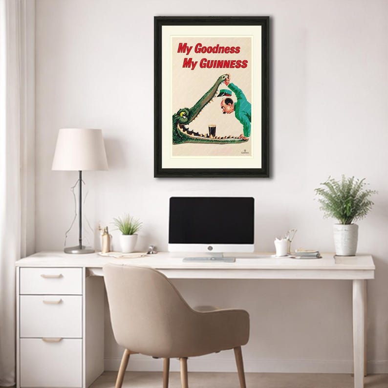 May include: Framed vintage Guinness advert. A man in green pours a pint of Guinness into an alligator's mouth. The text "My Goodness My Guinness" is in red. The artwork is framed in black, a classic piece of advertising.