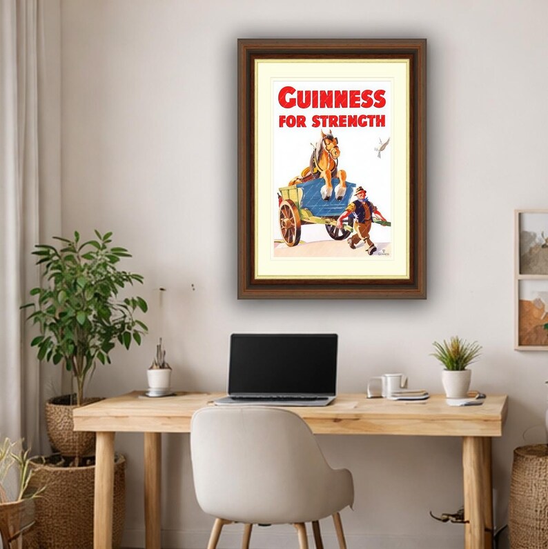 K&ouml;nnte beinhalten: Gerahmte Vintage-Guinness-Werbung. Das Kunstwerk zeigt einen Pferdewagen mit einem Mann, der daneben herl&auml;uft. Der Text "Guinness For Strength" ist rot. Der Rahmen ist braun.