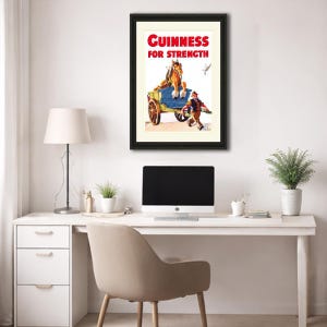 K&ouml;nnte beinhalten: Gerahmte Vintage-Guinness-Werbung. Das Poster zeigt ein Pferd, das einen Wagen zieht, mit einem Mann, der daneben rennt. Der Text "Guinness For Strength" ist rot. Das Kunstwerk ist vor einem cremefarbenen Hintergrund und schwarz gerahmt.