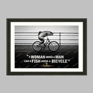 May include: Black and white framed wall art print. The image features a fish riding a bicycle with the quote "A woman needs a man like a fish needs a bicycle." The Guinness logo is at the bottom.