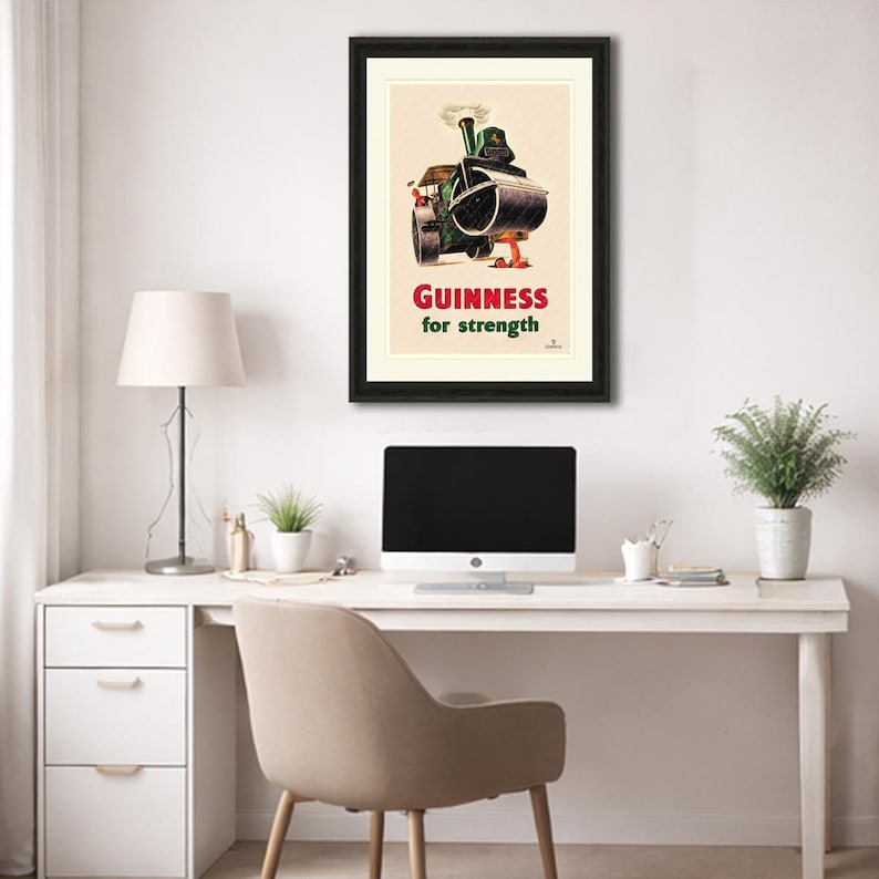 Puede incluir: Anuncio vintage enmarcado de Guinness. La obra de arte presenta un rodillo de vapor con un barril de Guinness, con el texto "Guinness for strength" en rojo y blanco. El p&oacute;ster est&aacute; en un marco negro.
