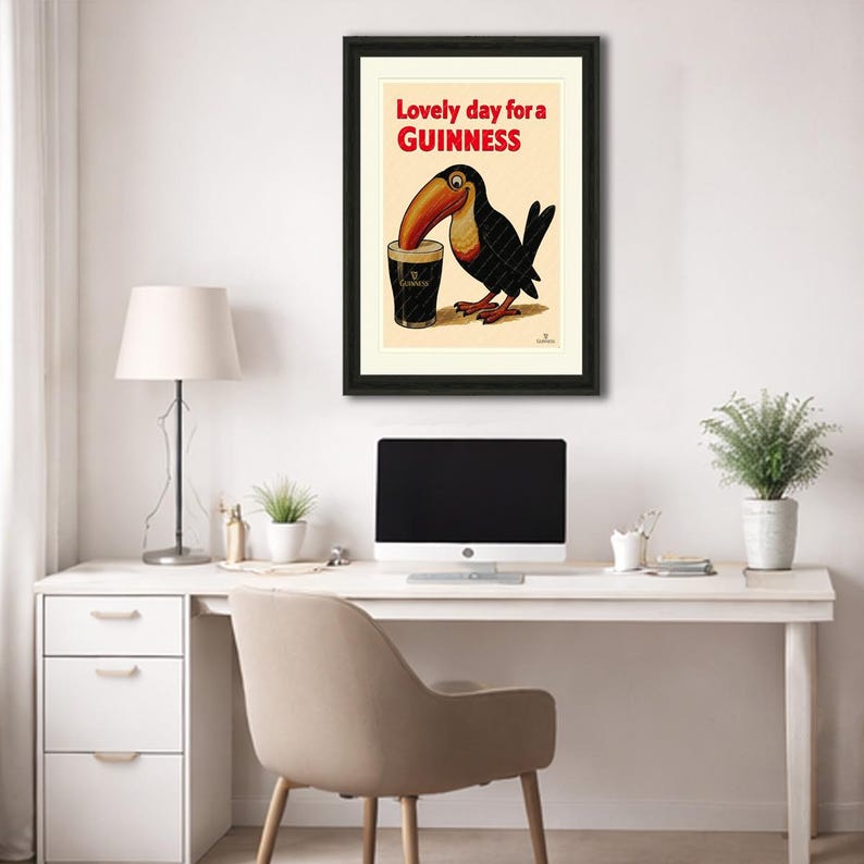 May include: Framed vintage Guinness advertisement featuring a toucan with a long orange beak drinking from a pint glass. The text "Lovely day for a Guinness" is in red and black. The artwork is in a black frame.