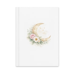 Op de afbeelding: Een wit notitieboek met een aquarel illustratie van een halve maan en bloemmotieven. De maan heeft een warme goudkleur, versierd met roze en witte bloemen en hangende sterren. Het ontwerp is gecentreerd op de omslag van het notitieboek.