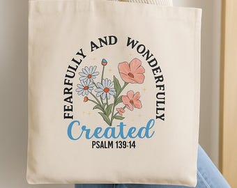 May include: Cream-colored tote bag with a floral design and the words "FEARFULLY AND WONDERFULLY CREATED" in a circular arrangement. The text "PSALM 139:14" is below "Created". The design features daisies and pink flowers.
