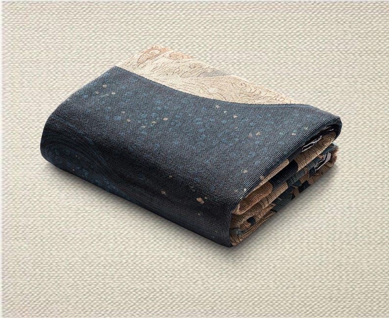 May include: Folded textile with a navy blue and tan color scheme. The navy blue section has a speckled pattern with small tan dots. The tan section has a detailed, patterned design. The textile is folded neatly.