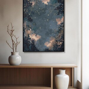 May include: A framed art print shows a night sky with constellations and golden stars, framed by silhouetted trees. The artwork is displayed above a wooden console with white vases. The print's colour palette includes dark blue and soft peach.