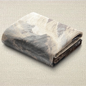May include: Folded textile with a landscape design in shades of gray, brown, and beige. The fabric is folded neatly, showcasing the detailed pattern. The overall aesthetic is neutral and earthy.