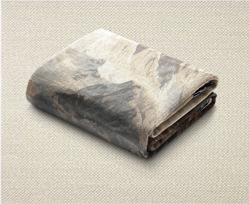 May include: Folded textile with a landscape design in shades of gray, brown, and beige. The fabric is folded neatly, showcasing the detailed pattern. The overall aesthetic is neutral and earthy.