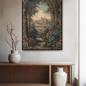May include: A framed landscape print depicts a castle nestled in a valley, framed by lush trees and foliage. The artwork features a muted color palette with shades of green, brown, and blue, creating a vintage aesthetic. The print is displayed above a wooden console.
