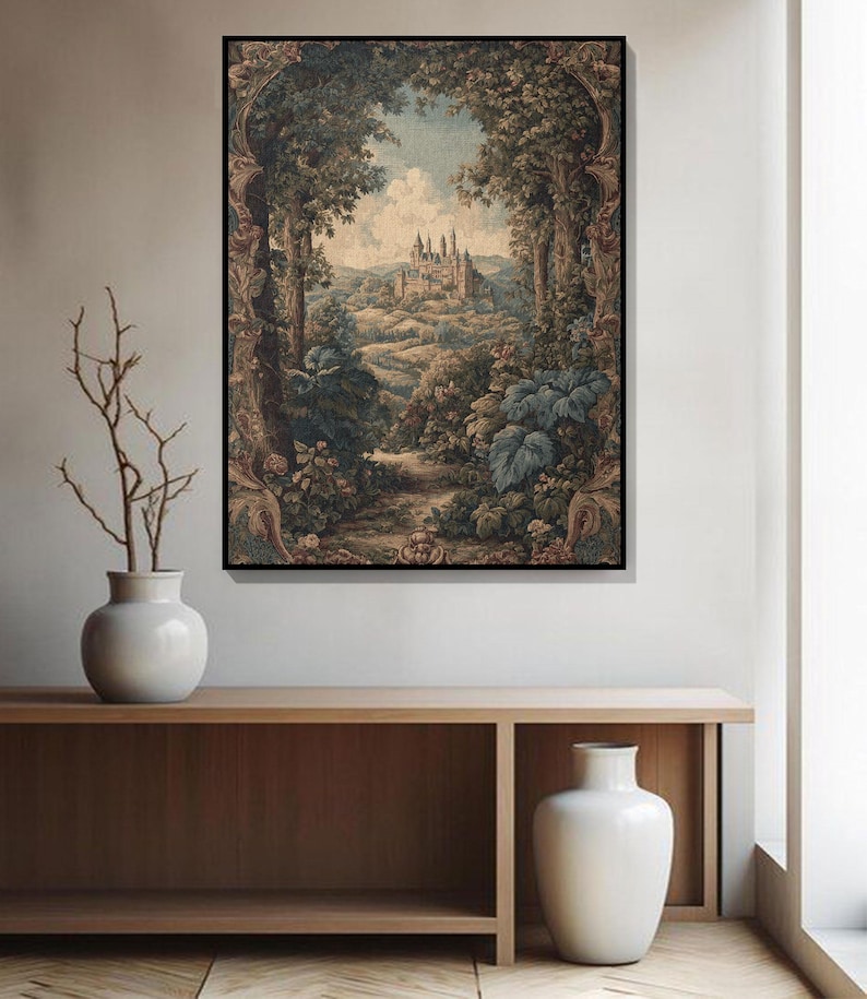 May include: A framed landscape print depicts a castle nestled in a valley, framed by lush trees and foliage. The artwork features a muted color palette with shades of green, brown, and blue, creating a vintage aesthetic. The print is displayed above a wooden console.