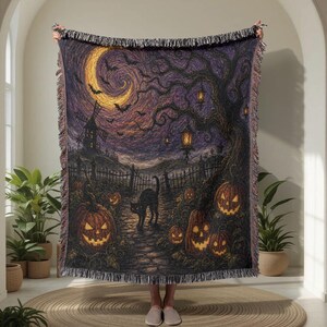 May include: A woven throw blanket featuring a dark Halloween scene with a black cat, glowing jack-o'-lanterns, a windmill, and a crescent moon in a purple and black sky. The blanket has a fringed edge and a detailed, textured tapestry-style design.