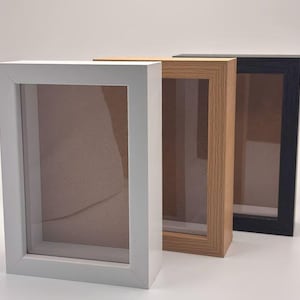 Pode incluir: Tr&ecirc;s molduras de caixa de sombra em branco, madeira natural e preto. Cada moldura tem formato retangular com frente de vidro e interior rebaixado. As molduras s&atilde;o projetadas para exibir itens e criar um efeito 3D.