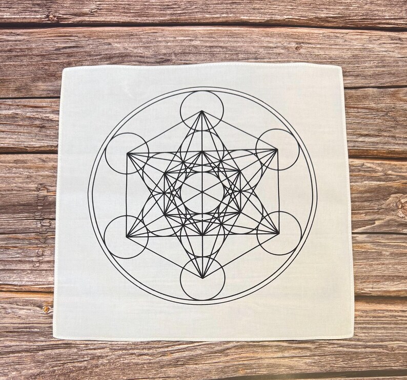 May include: Square, off-white cloth featuring a black Metatron's Cube design. The geometric pattern includes interconnected circles, lines, and a central star shape. The cloth is likely used for spiritual or decorative purposes.