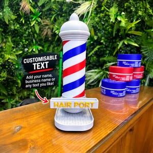 Peut inclure: Un poteau de barbier cylindrique avec des rayures diagonales rouges, blanches et bleues, surmonté d'un dôme blanc. Un panneau rectangulaire blanc fixé à la base porte le texte jaune HAIR PORT. Plusieurs pots de cire capillaire sont présents.