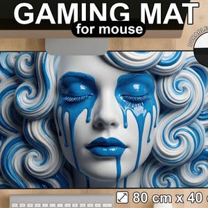 Puede incluir: Alfombrilla de ratón para juegos con la imagen de un rostro femenino con pintura azul goteando de ojos y labios, rodeado de cabello arremolinado azul y blanco. La alfombrilla mide 80 cm x 40 cm y tiene el texto "GAMING MAT for mouse".