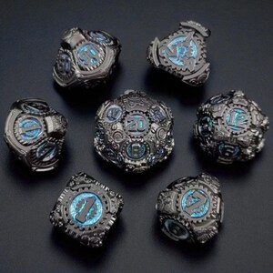 May include: Set of seven metal dice with a steampunk design. The dice are dark gray with intricate gear details and blue illuminated numbers. The dice include a D4, D6, D8, D10, D12, D20, and a percentile die.