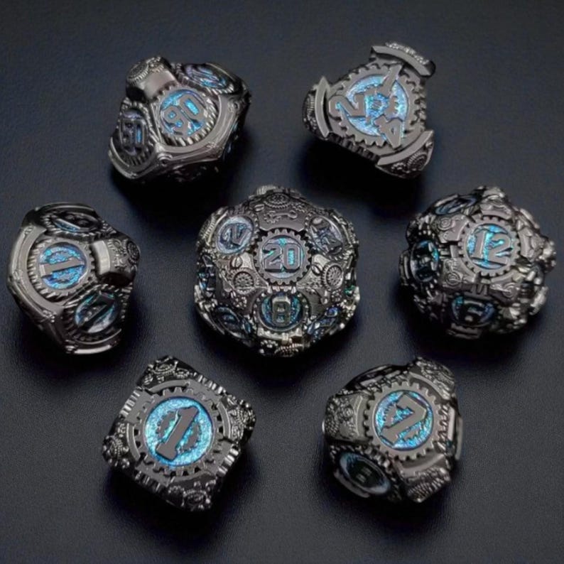 May include: Set of seven metal dice with a steampunk design. The dice are dark gray with intricate gear details and blue illuminated numbers. The dice include a D4, D6, D8, D10, D12, D20, and a percentile die.