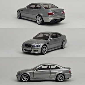 Könnte beinhalten: Ein silbernes Modellauto aus Druckguss mit zweitüriger Coupé-Karosserie, detaillierten Speichenrädern, klaren Fenstern und roten Rückleuchten. Das Fahrzeug zeigt das charakteristische Frontgrill-Design, seitliche Lüftungsschlitze und eine glatte Metallic-Lackierung.