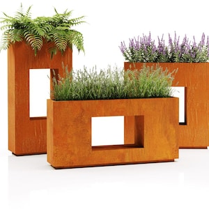 Peut inclure: Trois jardinières rectangulaires en métal couleur rouille avec des découpes carrées. Chaque jardinière contient différentes plantes vertes, dont des fougères et de la lavande. Les jardinières sont de hauteurs et de largeurs variables.