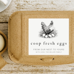May include: A brown egg box with a white label showing a detailed drawing of a rooster and eggs. The label says "coop fresh eggs" and "From our nest to yours". The Cluckery Company logo is in the bottom right corner.