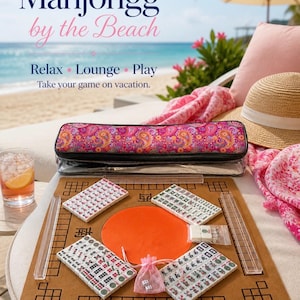 May include: A Mahjongg game set on a beach setting. The set includes tiles, a game board, and a carrying case with a paisley design. The text on the image says "Mahjongg by the Beach" and "Relax, Lounge, Play, Take your game on vacation."