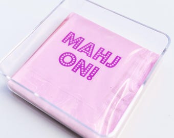 May include: A pink paper napkin with the words "Mahj On!" printed in pink with white polka dots.