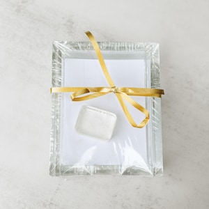 May include: A clear glass picture frame with a gold ribbon tied around it. The frame is empty and ready for a photo.