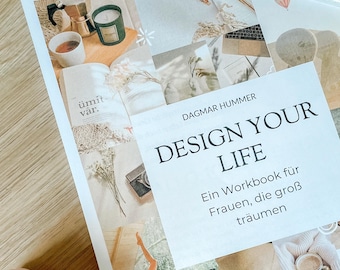 May include: A workbook titled "DESIGN YOUR LIFE" by Dagmar Hummer, with the text "Ein Workbook für Frauen, die groß träumen." The image includes a coffee cup, a candle, and a pen.
