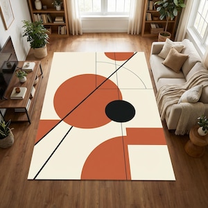 May include: A large rectangular rug with a cream background and a geometric design. It features rust-coloured circles, a black circle, and black lines. The rug is in a living room setting with a sofa and wooden furniture.