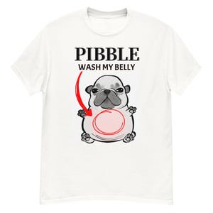 Pode incluir: Camiseta branca com um desenho de pug e o texto "PIBBLE WASH MY BELLY". O pug é cinza e branco, com uma seta vermelha apontando para sua barriga. O design está centralizado na frente.