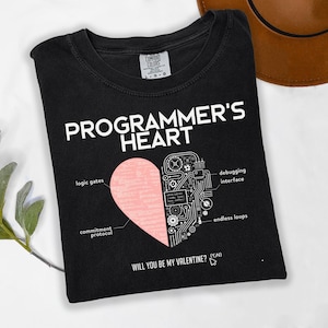 May include: Black t-shirt with the text "PROGRAMMER'S HEART" in white. A pink heart graphic is split, with one side showing code and the other side labeled with programming terms. The text "WILL YOU BE MY VALENTINE? (Y/N)" is at the bottom.