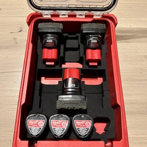 Può includere: Una valigetta rossa Milwaukee con coperchio trasparente, contenente due batterie per utensili elettrici nere e rosse, una batteria rossa e nera e tre batterie nere e rosse. La valigetta è aperta, rivelando gli utensili all'interno.