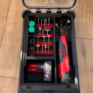 Può includere: Una valigetta per utensili in plastica nera e trasparente con una varietà di accessori per utensili rotanti. La valigetta contiene un utensile rotante rosso e nero, una batteria e varie punte e accessori di varie forme e dimensioni.