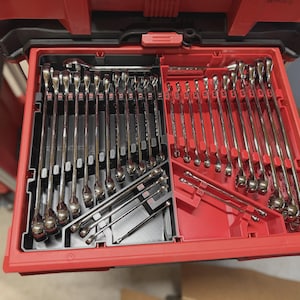 May include: A red and black tool storage drawer containing a large collection of chrome-plated combination wrenches organized in custom-molded slots. The wrenches are arranged in rows and diagonal sections, featuring various sizes with clearly visible markings.
