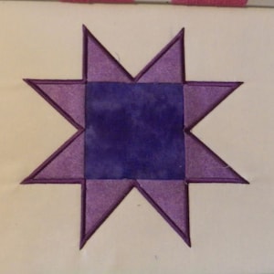 May include: A purple and lavender star-shaped quilt block with a darker purple center square.