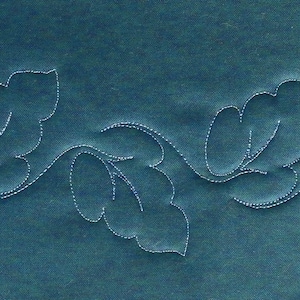 May include: A teal fabric displays a white, embroidered design of stylized leaves and vines. The delicate stitching creates a textured, linear pattern across the surface. The leaves are detailed with internal veins.