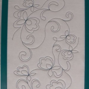 Puede incluir: Un aro de bordado blanco con un diseño floral cosido con hilo negro. El aro está etiquetado como "8x12 hoop".