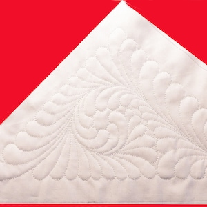 May include: A white fabric triangle with a quilted design of stylized feathers. The quilting is done in a light gray thread.