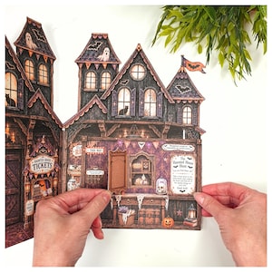May include: A multi-paneled paper haunted house display featuring intricate illustrations of ghosts, bats, and black cats. The structure includes a ticket booth, a "Haunted House Hunt" sign, and a small hinged door that opens to reveal interior details.