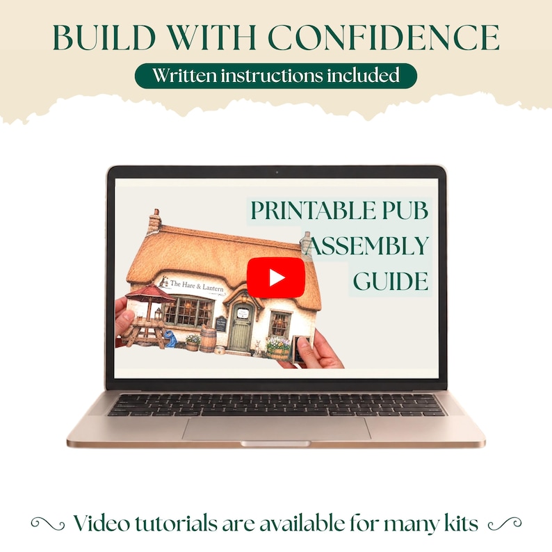 May include: A laptop screen displays a printable pub assembly guide featuring a miniature thatched-roof building labeled The Hare & Lantern. The screen includes a red play button icon, and the text reads BUILD WITH CONFIDENCE, Written instructions included, and Video tutorials are available for many kits.