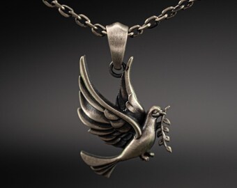 May include: A silver-toned metal pendant shaped like a dove in flight, carrying a small leafy branch in its beak. The pendant is suspended from a matching silver-toned metal chain link necklace, featuring a brushed, antiqued finish throughout.