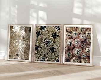 May include: Three framed art prints with gold and silver tones. One print features a mosaic design, another has a star pattern, and the third showcases a cluster of disco balls. The frames are a light wood colour.